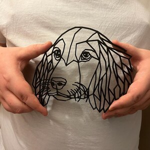 May include: A black geometric design of a dog's head on a white t-shirt.