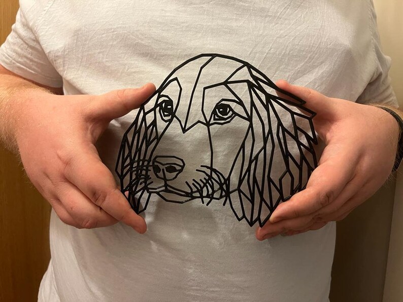 May include: A black geometric design of a dog's head on a white t-shirt.