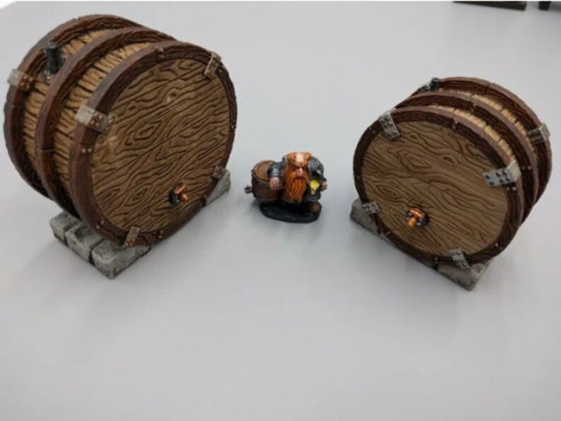 May include: Three wooden barrels with metal accents and a small figurine of a dwarf holding a barrel. The barrels are brown and have a wood grain texture. The dwarf is wearing a red and brown outfit and has a beard.