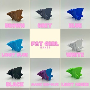 May include: A collection of 12 small, colourful, 3D printed sculptures in the shape of a stylised dinosaur. The sculptures are arranged in a grid pattern and labelled with their corresponding colours: green, orange, red, brown, grey, blue, light blue, white, black, magic red-blue, light green, pink, yellow, and purple.