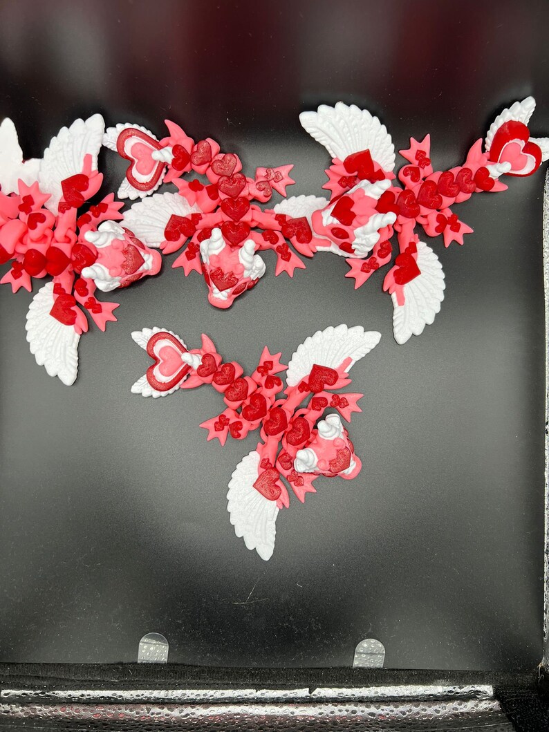 Puede incluir: Tres adornos de coraz&oacute;n alados de color rosa y blanco con un dise&ntilde;o de coraz&oacute;n. Los adornos est&aacute;n hechos de un material suave y flexible y son perfectos para las decoraciones del D&iacute;a de San Valent&iacute;n.