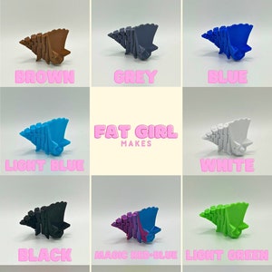 May include: A collection of 12 colorful 3D printed dinosaur toys in various colors, including green, orange, red, brown, grey, blue, light blue, white, black, magic red-blue, light green, pink, yellow, and purple. The toys are arranged in a grid pattern with the text "FAT GIRL MAKES" in the center.
