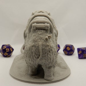May include: A gray 3D printed miniature of a furry creature with a saddle and a rope attached to the back. The creature is standing on a round base. There are four purple dice with gold numbers in the background.