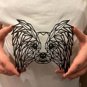 Puede incluir: Una silueta geom&eacute;trica negra de un perro papillon con orejas largas y colgantes. La silueta est&aacute; hecha de tri&aacute;ngulos y es un dise&ntilde;o moderno y elegante.