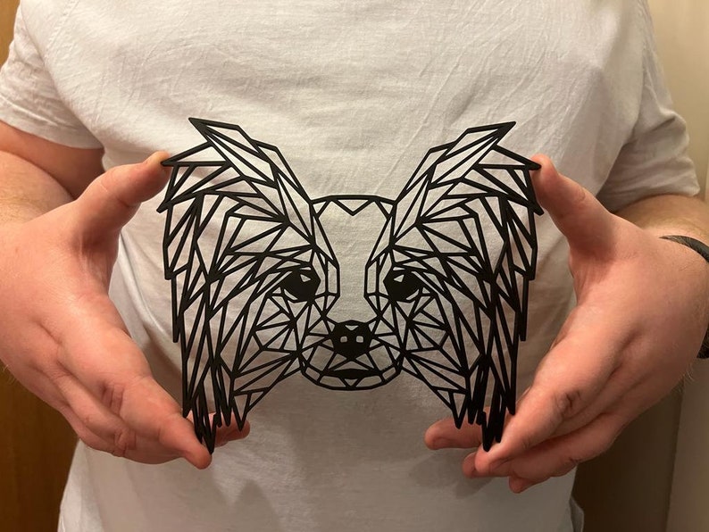 Puede incluir: Una silueta geom&eacute;trica negra de un perro papillon con orejas largas y colgantes. La silueta est&aacute; hecha de tri&aacute;ngulos y es un dise&ntilde;o moderno y elegante.