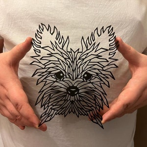 May include: A black and white geometric paper cut-out of a Yorkshire Terrier dog's face.