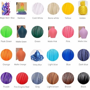 May include: Assortment of 18 colors of filament for 3D printing. The filament is wound into spools and displayed in a grid pattern. The colors include: Magic Red + Blue, Rainbow, Cold White, Bone White, Yellow, Golden, Peak Green, Matte Green, Green, Matte Pink, Pink, Matte Lilac, Orange, Matte Orange, Shiny Blue, Light Blue, Blue, Dark Blue, Purple, Fire Engine Red, Gray, Light Brown, Brown, and Black.