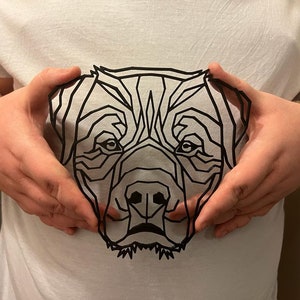 May include: A black and white geometric illustration of a dog's face, printed on a white t-shirt.