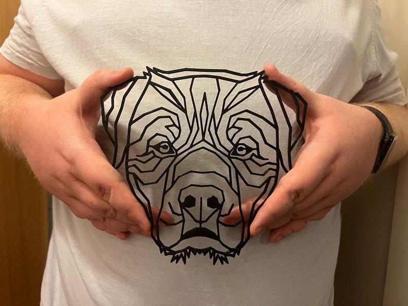May include: A black and white geometric illustration of a dog's face, printed on a white t-shirt.
