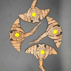 May include: Four brown wooden stingray toys with yellow accents. Each stingray has a segmented body and a long tail.