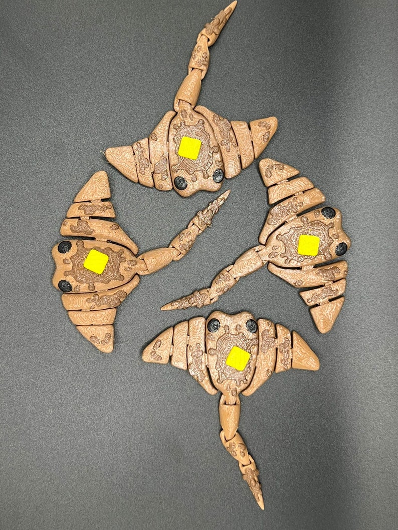 May include: Four brown wooden stingray toys with yellow accents. Each stingray has a segmented body and a long tail.