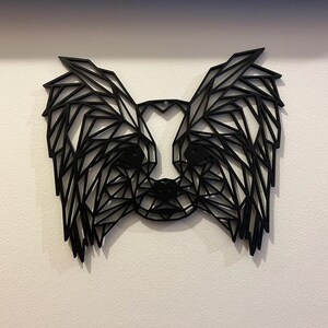 Puede incluir: Arte de pared geom&eacute;trico negro que representa la cabeza de un perro con orejas grandes. El arte est&aacute; hecho de metal negro delgado y est&aacute; montado en una pared blanca.