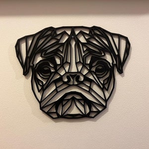 May include: Black geometric wall art of a pug dog's face. The art is made of metal and has a modern, minimalist style.