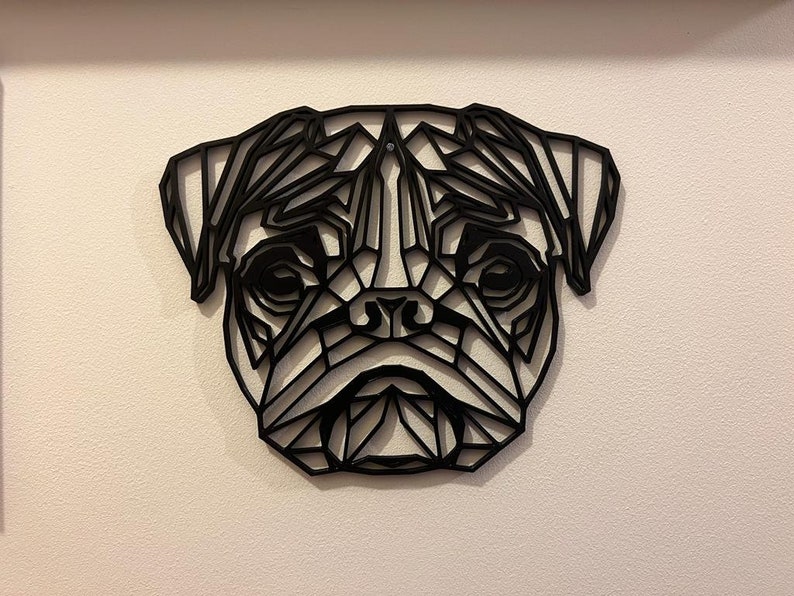 May include: Black geometric wall art of a pug dog's face. The art is made of metal and has a modern, minimalist style.