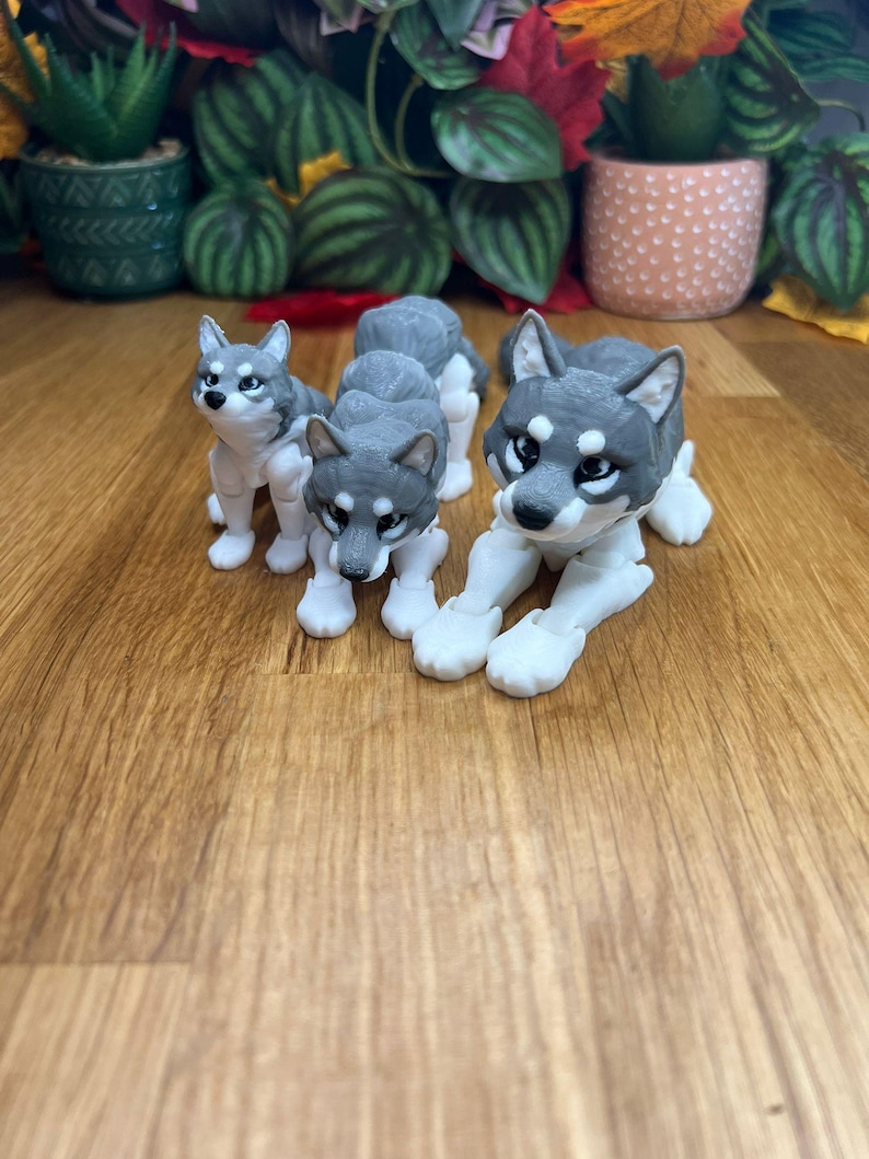Peut inclure: Trois figurines de loup grises et blanches avec des membres articul&eacute;s. Les loups sont en position assise et couch&eacute;e.