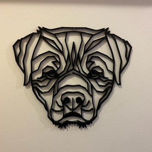 May include: Black geometric dog head wall art. The dog's head is made of metal and is in a minimalist style.