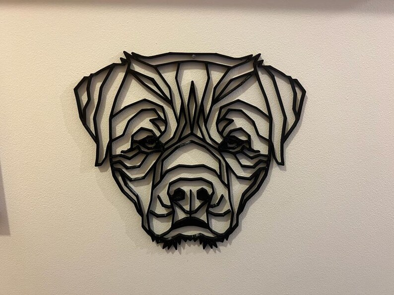 May include: Black geometric dog head wall art. The dog's head is made of metal and is in a minimalist style.