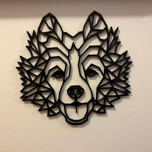 Puede incluir: Decoraci&oacute;n de pared de cabeza de lobo geom&eacute;trico negro. La cabeza de lobo est&aacute; hecha de una serie de tri&aacute;ngulos que crean un efecto 3D.