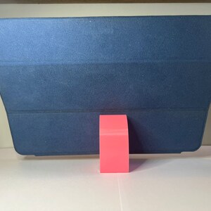 May include: A dark blue tablet case with a pink stand. The case is folded to create a stand for the tablet.