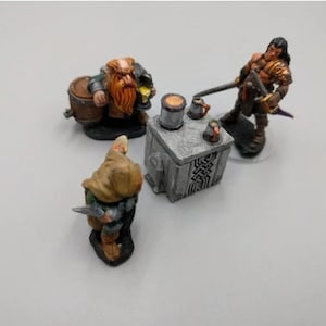 May include: A miniature scene with three figures: a red-haired dwarf holding a barrel, a cloaked figure with a dagger, and a warrior with a sword and shield. The figures are gathered around a small stone table with mugs and a tankard.