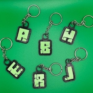 May include: Six black keychains with green glow-in-the-dark letters A, E, F, H, I, and J.
