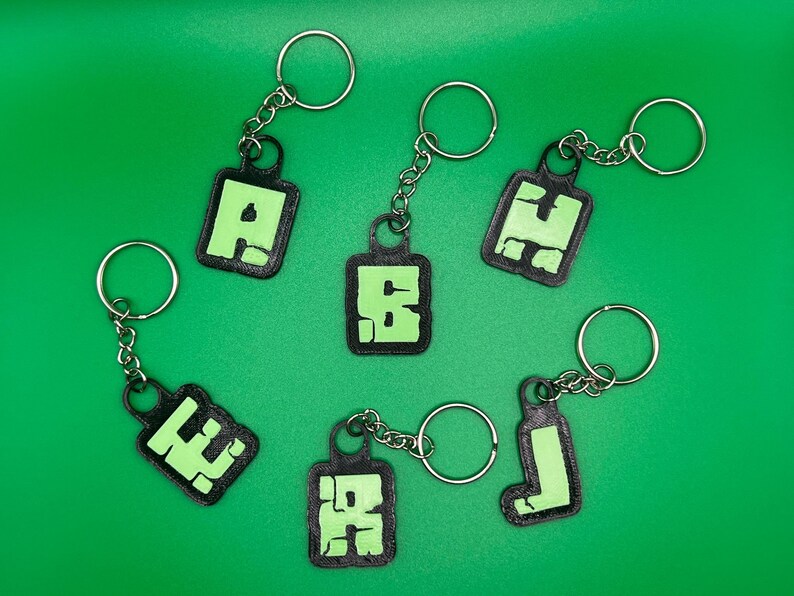 May include: Six black keychains with green glow-in-the-dark letters A, E, F, H, I, and J.