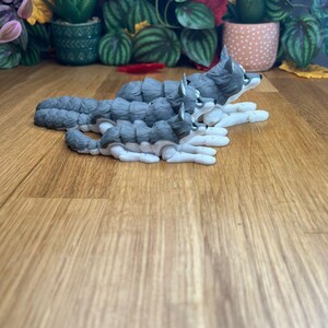 Peut inclure: Trois figurines de chien husky gris et blanc, dispos&eacute;es en ligne du plus grand au plus petit, le plus grand chien regardant vers la droite.