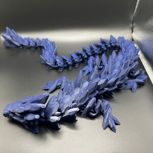 May include: A 3D printed blue dragon figurine with a spiky, crystalline texture. The dragon is curled up in a resting pose.