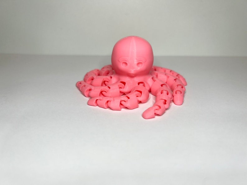 以下が含まれることがあります： セグメント化されたボディと8本の触手を持つピンクの3Dプリントされたタコ