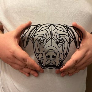 May include: A black and white geometric design of a dog's head, printed on a white t-shirt.