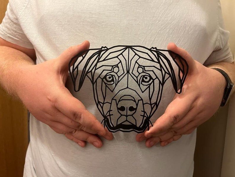 May include: A black and white geometric design of a dog's head, printed on a white t-shirt.