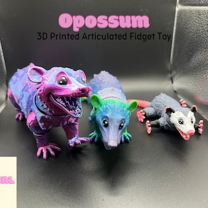 May include: Three 3D printed articulated opossum fidget toys. The opossums are in different colors and poses. The text "Opossum 3D Printed Articulated Fidget Toy" is above the toys. The text "Fat Girl Makes" is below the toys.