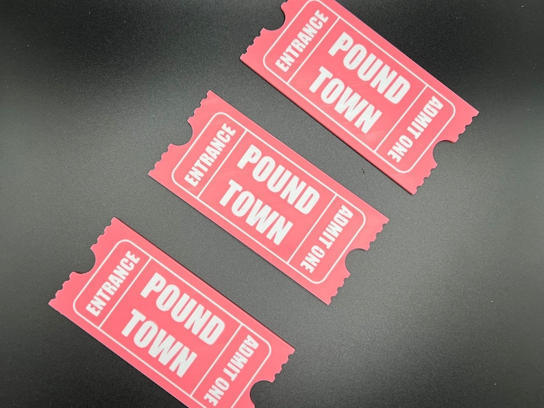 Puede incluir: Tres boletos de papel rosa con el texto "Entrance", "Pound Town" y "Admit One" impreso en ellos.