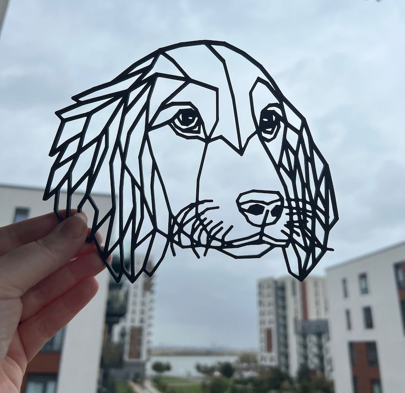 May include: Black and white geometric line art illustration of a dog's head. The dog has floppy ears and a long snout.