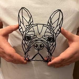 May include: A black paper cut-out of a French bulldog's head, with geometric shapes forming the outline of the dog's face.