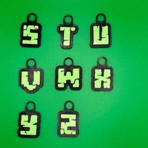 May include: Nine black keychains with green letters spelling out "STUVWXYZ" on a green background.