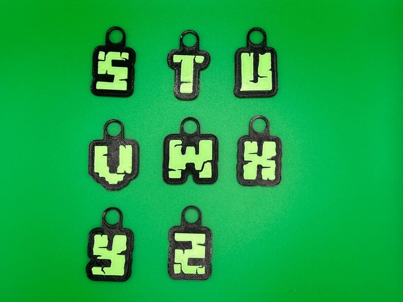 May include: Nine black keychains with green letters spelling out "STUVWXYZ" on a green background.