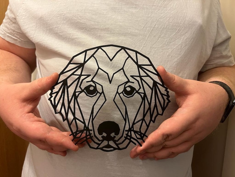Pu&ograve; includere: Un design geometrico in bianco e nero di un muso di cane su una maglietta bianca.