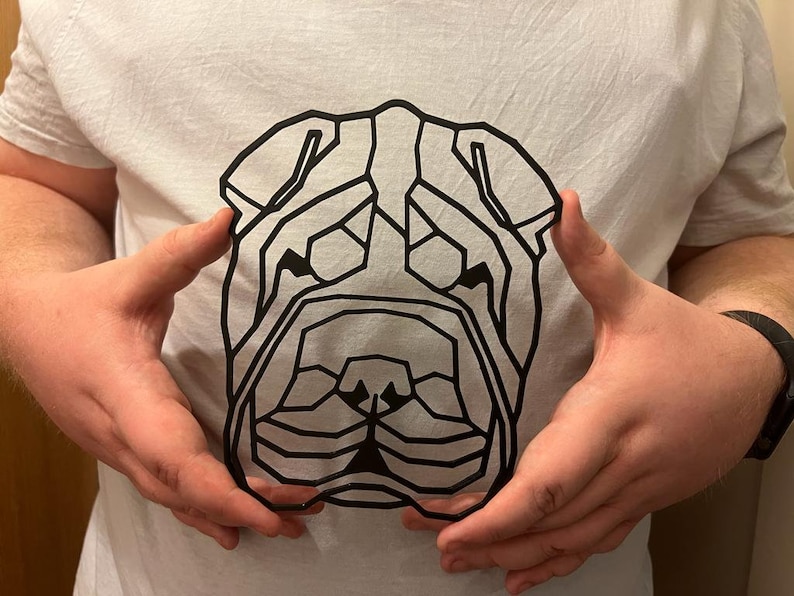 K&ouml;nnte beinhalten: Ein wei&szlig;es T-Shirt mit einem geometrischen Schwarz-Wei&szlig;-Design eines Shar-Pei-Hunde-Kopfes.