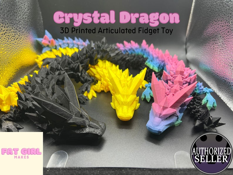 May include: Four 3D printed articulated fidget toys shaped like dragons. The dragons are in black, yellow, pink, and blue with a gradient effect. The text "Crystal Dragon 3D Printed Articulated Fidget Toy" is at the top of the image. The text "Fat Girl Makes" is in the bottom left corner of the image. The text "Authorized Seller" is in the bottom right corner of the image.