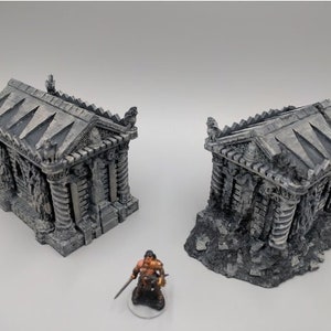 May include: Two detailed miniature stone mausoleums with intricate carvings and a weathered, aged appearance. The mausoleums are set on a base of broken stone and rubble.