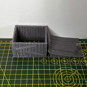 May include: A gray 3D printed wooden box with a hinged lid and a ramp. The box has a wood grain texture and is made of plastic.