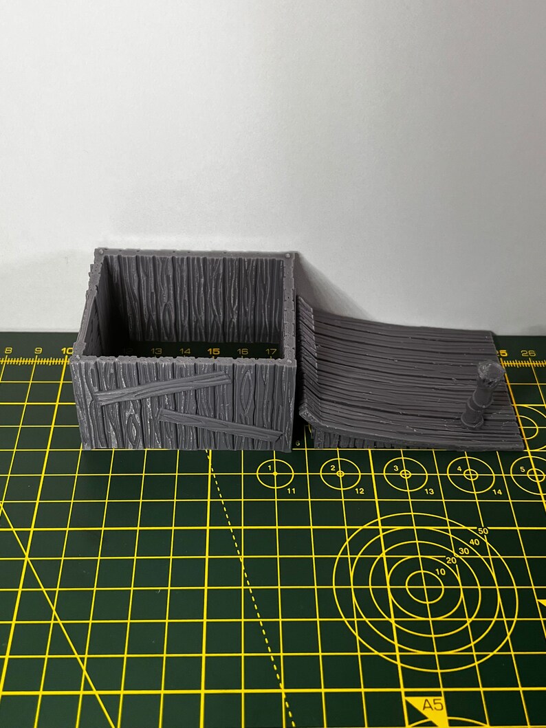 May include: A gray 3D printed wooden box with a hinged lid and a ramp. The box has a wood grain texture and is made of plastic.