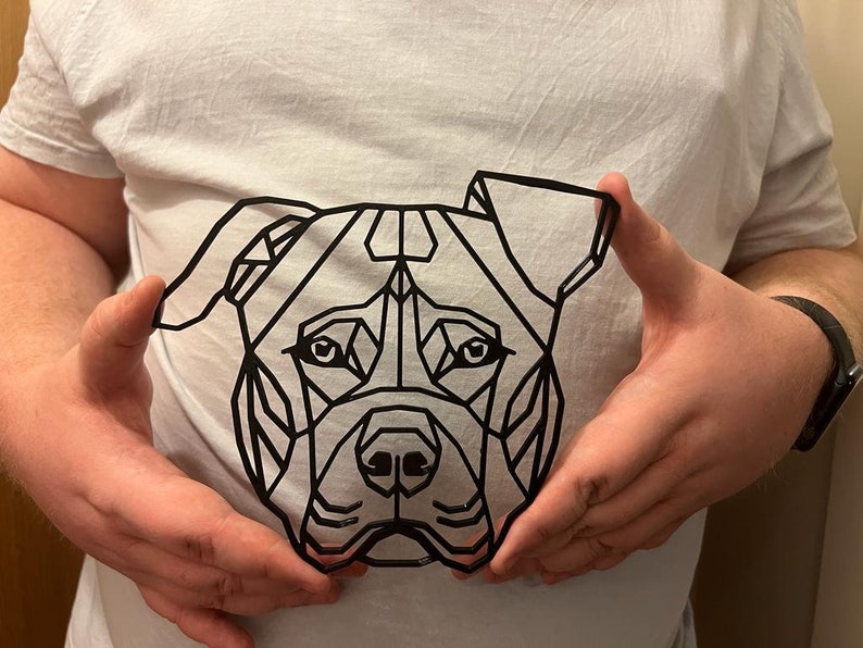 May include: A black and white geometric design of a dog's face. The design is made up of triangles and other geometric shapes.