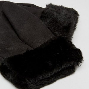 May include: Black faux fur hat with a suede brim and a thick faux fur band around the bottom.