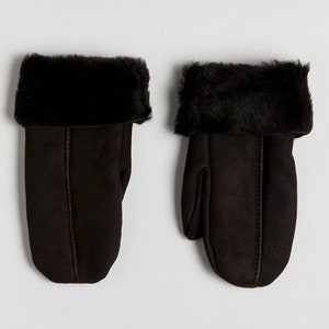 May include: A pair of black leather mittens with a faux fur cuff. The mittens are made of a soft, suede-like material.