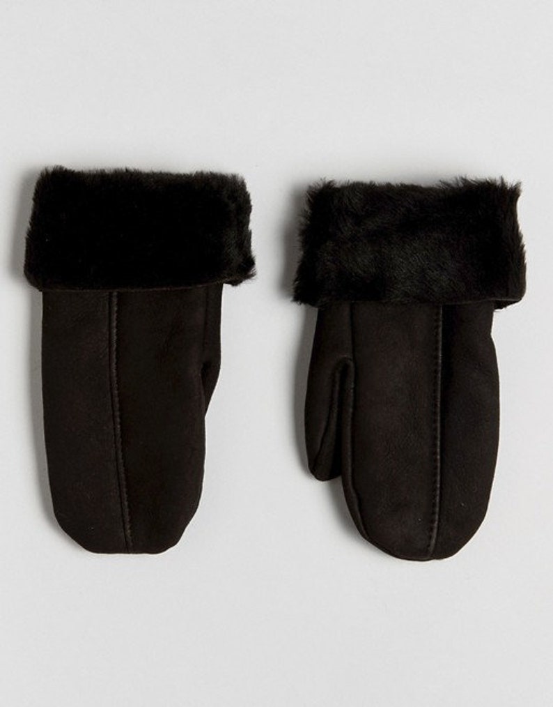 May include: A pair of black leather mittens with a faux fur cuff. The mittens are made of a soft, suede-like material.
