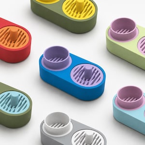 May include: A collection of oval-shaped, two-compartment organizers in various colors. Each unit features one solid cylindrical cup and one slotted circular base with a central post. The colors include red, blue, green, yellow, purple, and gray.
