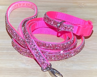 May include: Pink rhinestone dog collar and leash set. The collar and leash are both made of pink nylon and have a row of pink rhinestones around the edge.