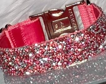 May include: A pink dog collar with a silver buckle and a pink and silver glitter design.
